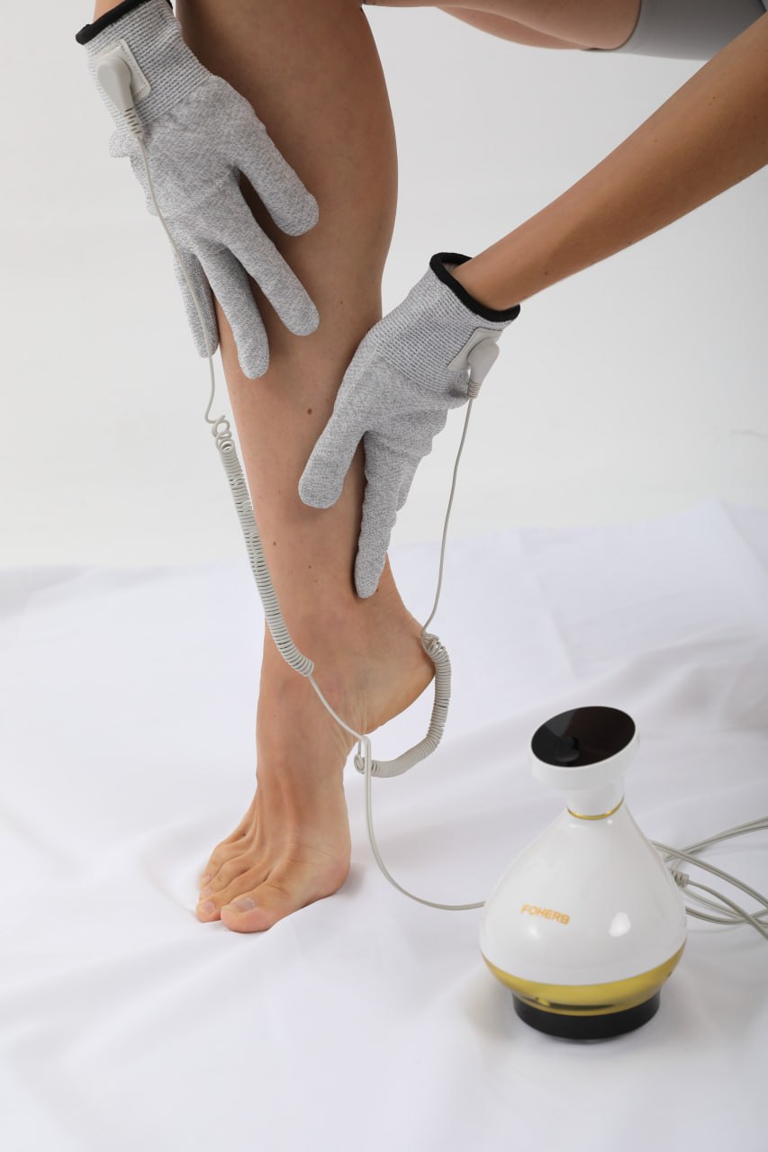 Bioenergetic Meridian Massager in use, with gloves applying treatment on leg, showcasing multifunctional therapy features.